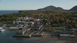 AX148_221E - 5.5K aerial stock footage flying over harbor along coastal town, hotels, houses and fall foliage, Bar Harbor, Maine