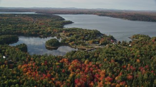 AX148_230 - 5.5K aerial stock footage flying over fall foliage toward a pond and coastal town, Bar Harbor, Maine