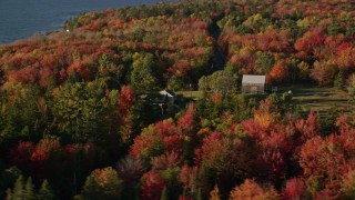 AX149_005 - 5.5K aerial stock footage flying by rural home and road among forest with fall foliage, Trenton, Maine