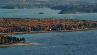 AX149_007 - 5.5K aerial stock footage flying by forest with colorful fall foliage along a cove, Trenton, Maine