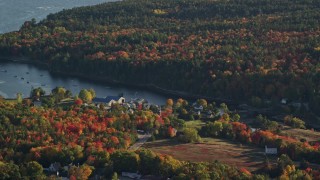 AX149_012 - 5.5K aerial stock footage flying by a coastal town toward the water surrounded by autumn trees, Blue Hill, Maine