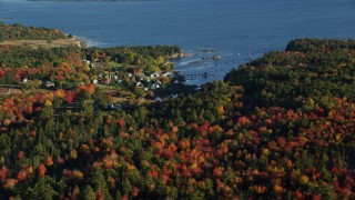 AX149_014 - 5.5K aerial stock footage flying over autumn forest away from a coastal neighborhood, Blue Hill, Maine