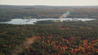 AX149_015 - 5.5K aerial stock footage flying over forest with fall foliage along a river, Blue Hill, Maine