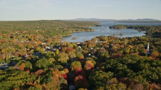 AX149_018E - 5.5K aerial stock footage flying by coastal town and harbor among fall foliage, Blue Hill, Maine