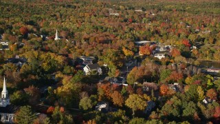 AX149_021 - 5.5K aerial stock footage flying along a small town with church steeples, nestled among fall foliage, Blue Hill, Maine
