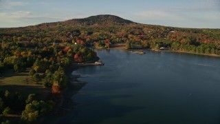 AX149_022 - 5.5K aerial stock footage flying away from coastal town among fall foliage and harbor, Blue Hill, Maine