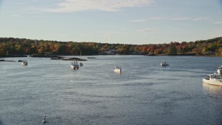 AX149_024E - 5.5K aerial stock footage flying over water with boats toward fall foliage, Blue Hill, Maine