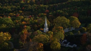 AX149_028 - 5.5K aerial stock footage orbiting church steeple in a small town with fall foliage, Blue Hill, Maine