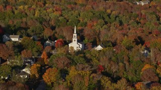 AX149_029 - 5.5K aerial stock footage flying away from a small town and white church among fall foliage, Blue Hill, Maine