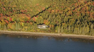 AX149_086E - 5.5K aerial stock footage flying by isolated waterfront home, colorful forest, autumn, Castine, Maine