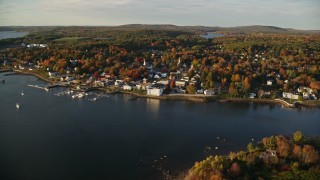 AX149_103E - 5.5K aerial stock footage flying by small coastal town, colorful trees in autumn, Bucksport, Maine