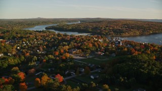 AX149_108E - 5.5K aerial stock footage flying over trees by a small town on Penobscot River, autumn, Bucksport, Maine