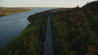 AX149_116E - 5.5K aerial stock footage flying over Route 3 along the river in autumn, Stockton Springs, Maine, sunset