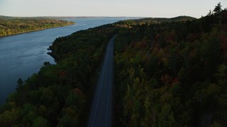 AX149_117 - 5.5K aerial stock footage flying over Route 3, colorful forest in autumn, Stockton Springs, Maine, sunset