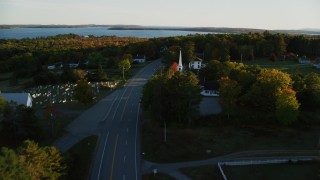 AX149_127 - 5.5K aerial stock footage flying over road, church and cemetery, autumn, Stockton Springs, Maine, sunset