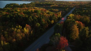 AX149_131 - 5.5K aerial stock footage tracking car on road through forest, autumn, Stockton Springs, Maine, sunset