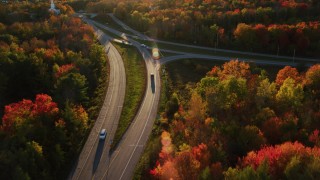 AX149_136 - 5.5K aerial stock footage of a car on road approaching a church, autumn, Stockton Springs, Maine, sunset