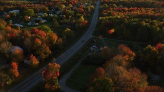 AX149_138 - 5.5K aerial stock footage tracking car on road through small town, autumn, Stockton Springs, Maine, sunset
