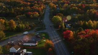 AX149_140 - 5.5K aerial stock footage tracking car on road with light traffic, through small town, autumn, Stockton Springs, Maine, sunset