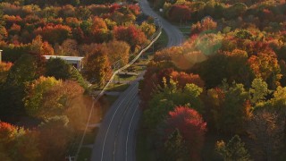 AX149_141E - 5.5K aerial stock footage tracking car on road through quaint town, autumn, Stockton Springs, Maine, sunset