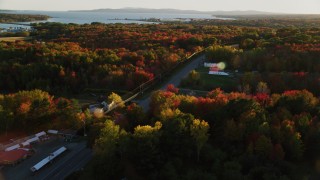 AX149_144 - 5.5K aerial stock footage tracking a car on road passing by small town, autumn, Stockton Springs, Maine, sunset
