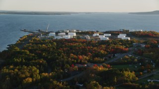 AX149_147 - 5.5K aerial stock footage flying by waterfront oil refinery and gas company, autumn, Searsport, Maine, sunset