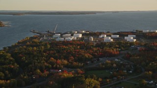AX149_147E - 5.5K aerial stock footage flying by waterfront oil refinery and gas company, autumn, Searsport, Maine, sunset