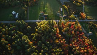 AX149_150 - 5.5K aerial stock footage of a bird's eye view over rural homes, forest in autumn, Searsport, Maine, sunset