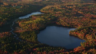AX149_153 - 5.5K aerial stock footage flying by ponds among colorful forest in autumn, Searsport, Maine, sunset