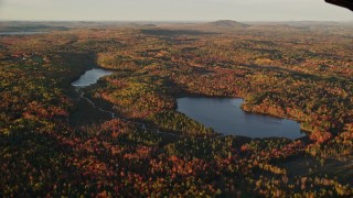 AX149_154 - 5.5K aerial stock footage flying by ponds surrounded by forest in autumn, Searsport, Maine, sunset