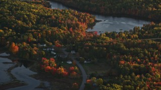AX149_157E - 5.5K aerial stock footage flying by ponds surrounded by forest in autumn, Belfast, Maine, sunset
