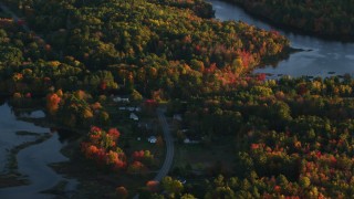 AX149_158 - 5.5K aerial stock footage flying away from pond and rural homes, forest in autumn, Belfast, Maine, sunset
