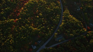 AX149_164 - 5.5K aerial stock footage of a bird's eye view over forest in autumn, rural homes, Belfast, Maine, sunset