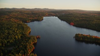 AX149_172 - 5.5K aerial stock footage flying over Quantabacook Lake, forest, autumn, Searsmont, Maine, sunset