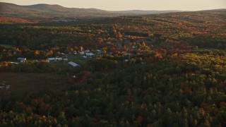 AX149_174E - 5.5K aerial stock footage approaching small rural town, colorful trees in autumn, Searsmont, Maine, sunset
