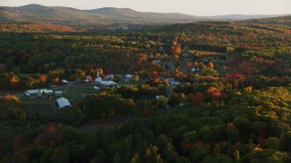 AX149_175 - 5.5K aerial stock footage approaching small rural town, colorful forest in autumn, Searsmont, Maine, sunset