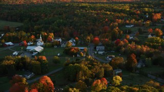 AX149_176 - 5.5K aerial stock footage flying by small rural town, colorful forest in autumn, Searsmont, Maine, sunset