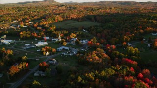 AX149_177 - 5.5K aerial stock footage orbiting small rural town near colorful forest, autumn, Searsmont, Maine, sunset