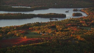 AX149_191E - 5.5K aerial stock footage flying by rural homes, Saint George Lake, autumn, Liberty, Maine, sunset