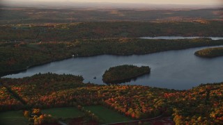 AX149_193 - 5.5K aerial stock footage flying by small forested islands, Saint George Lake, autumn, Liberty, Maine, sunset