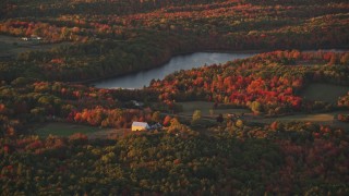 AX149_199 - 5.5K aerial stock footage flying by rural homes, forest and Beech Pond, autumn, Palermo, Maine, sunset