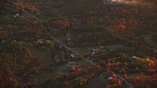 AX149_206 - 5.5K aerial stock footage flying by rural homes, Ridge Road, colorful trees in autumn, Windsor, Maine, sunset