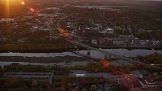 AX149_214 - 5.5K aerial stock footage approaching downtown, small bridge, Kennebec River, autumn, Augusta, Maine, sunset