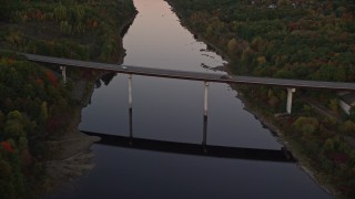 AX149_239E - 5.5K aerial stock footage approaching small bridge spanning Kennebec River, autumn, Augusta, Maine, twilight