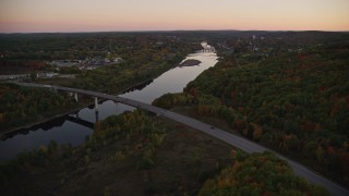 AX149_241E - 5.5K aerial stock footage flying by small bridge, Kennebec River, autumn, Augusta, Maine, twilight