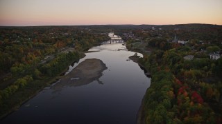AX149_243E - 5.5K aerial stock footage flying over colorful forest, approach Kennebec River, autumn, Augusta, Maine, twilight