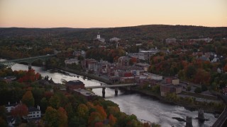 AX149_245E - 5.5K aerial stock footage flying by small bridge, Kennebec River, downtown, autumn, Augusta, Maine, twilight