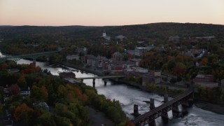 AX149_246 - 5.5K stock footage aerial video flying by small bridges on Kennebec River, downtown, autumn, Augusta, Maine, twilight