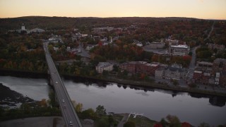 AX149_248 - 5.5K aerial stock footage flying by small bridges into downtown, Kennebec River, Autumn, Augusta, Maine, twilight