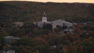 AX149_249E - 5.5K aerial stock footage flying by the Maine State House, dense trees, autumn, Augusta, Maine, twilight